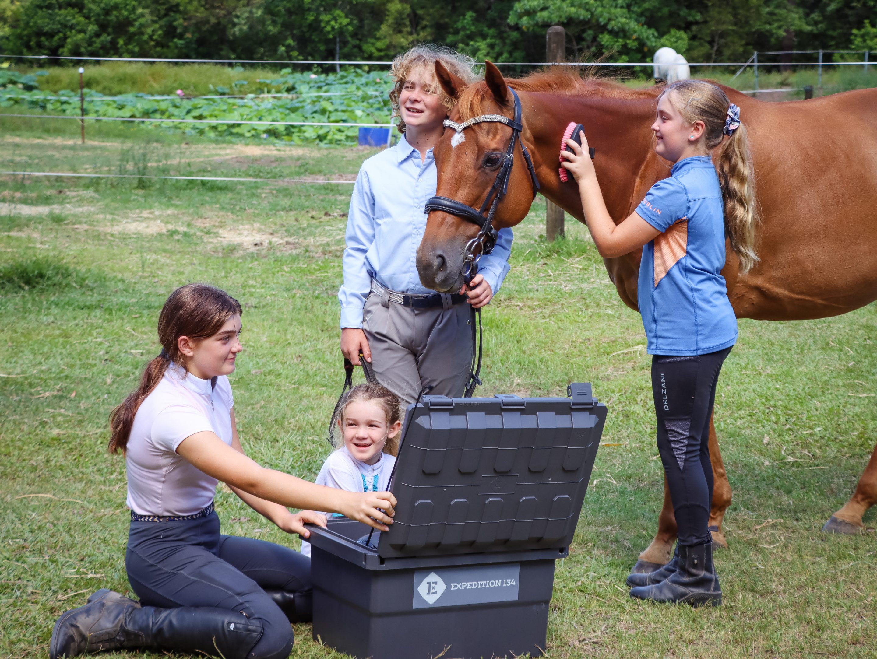Equestrian Kids holding a tack box with a horse