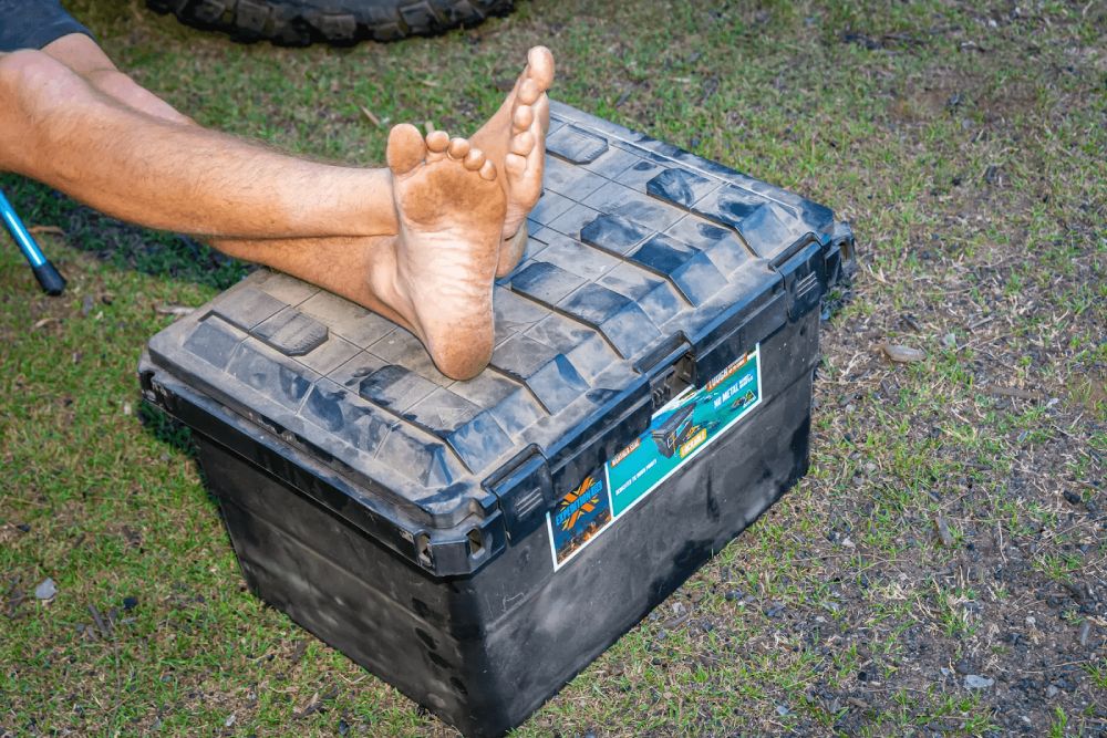 man with his feet on a quad bike storage box